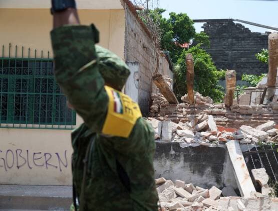 (170910) -- JUCHITAN (MEXICO), Sept. 10, 2017 -- A soldier walks past a damaged house after an earthquake hit in Juchitan, Oaxaca state, Mexico, Sept. 9, 2017. A powerful earthquake measuring 8.2 on the Richter scale struck off Mexico s southern coast late Thursday night, killing 90 people. ) MEXICO-OAXACA-JUCHITAN-EARTHQUAKE DanxHang 