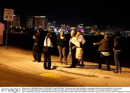 Spectators and hotel residents congregate around a police road block on the south side of Las Vegas Boulevard after apparent gun fire was heard around the Mandalay Bay Resort and Casino in Las Vegas, Nevada on October 1, 2017. More than 20 people were killed and at least 100 others injured after a gunman opened fire Sunday night at a country music festival opposite the Mandalay Bay hotel and resort on the Las Vegas Strip, authorities said.  LAV2017100208 JAMESxATOA
