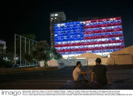 Israelis sit in Rabin Square with the colors of the American flag lit up on the Tel Aviv City Hall in honor of the victims of a shooting attack in Las Vegas, Nevada, in Tel Aviv, Israel, October 2, 2017. A gunman opened fire on a music festival leaving at least 58 dead and over 500 wounded.  JER2017100222 DEBBIExHILL