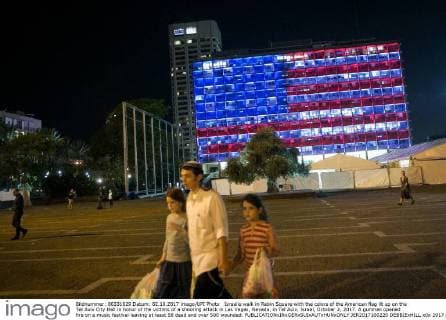 Israelis walk in Rabin Square with the colors of the American flag lit up on the Tel Aviv City Hall in honor of the victims of a shooting attack in Las Vegas, Nevada, in Tel Aviv, Israel, October 2, 2017. A gunman opened fire on a music festival leaving at least 58 dead and over 500 wounded.  JER2017100220 DEBBIExHILL