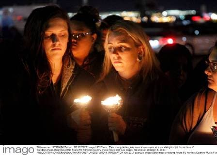 Two young ladies join several mourners at a candlelight vigil for victims of Sundays mass shooting at the Route 91 Harvest country music festival in Las Vegas, Nevada on October 2, 2017.  LAV2017100249 JAMESxATOA