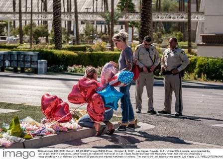October 3, 2017 - Las Vegas, Nevada, U.S - Unidentified people, accompanied by Las Vegas Sheriff s deputies, place flowers at makeshift memorial on Las Vegas Boulevard near the Mandalay Hotel and the site of Sunday s mass shooting which claimed the lives of 59 people and injured hundreds of others. The area is still an active crime scene. Las Vegas U.S. - ZUMAo102 20171003_zap_o102_009 Copyright: xNickxOttox