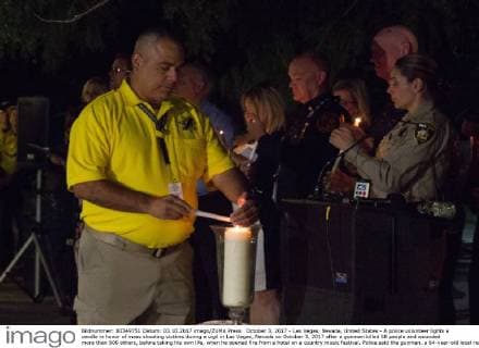 October 3, 2017 - Las Vegas, Nevada, United States - A police volunteer lights a candle in honor of mass shooting victims during a vigil in Las Vegas, Nevada on October 3, 2017 after a gunman killed 58 people and wounded more than 500 others, before taking his own life, when he opened fire from a hotel on a country music festival. Police said the gunman, a 64-year-old local resident named as Stephen Paddock, had been killed after a SWAT team responded to reports of multiple gunfire from the 32nd floor of the Mandalay Bay, a hotel-casino next to the concert venue. Las Vegas United States - ZUMAn230 20171003_zaa_n230_769 Copyright: xEmilyxMollix