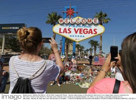 Women take photos at the historic Welcome to Las Vegas Sign where a memorial for the slain victims of the Route 91 Harvest music festival mass shooting is located October 19, 2017, in Las Vegas. A gunman opened fire on the music, leaving 58 dead and over 500 injured on October 1.  LAV20171019019 RONDAxCHURCHILL