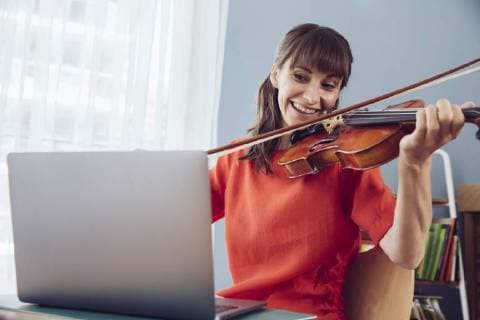 Woman using laptop to play a song on a violin model released Symbolfoto property released  MFF03793