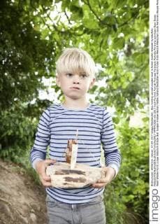 Boy holding carved wooden boat in forest model released Symbolfoto  MFRF01056