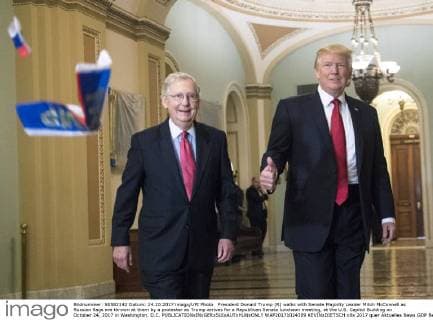 President Donald Trump (R) walks with Senate Majority Leader Mitch McConnell as Russian flags are thrown at them by a protester as Trump arrives for a Republican Senate luncheon meeting, at the U.S. Capitol Building on October 24, 2017 in Washington, D.C.  WAP20171024309 KEVINxDIETSCH