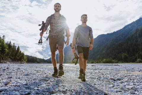 Germany Bavaria two hikers walking in dry creek bed at backlight model released Symbolfoto  DIGF02823