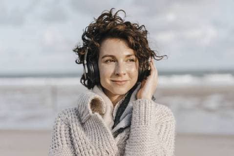 Smiling woman on the beach with headphones model released Symbolfoto  KNSF02557