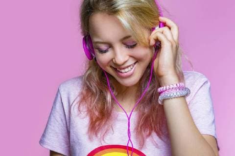 Portrait of young woman listening to music with headphones in front of pink background model released Symbolfoto property released  MGIF00099