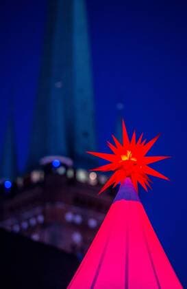 Luebeck Christmas market a Christmas star lit at 24 11 2016 on the Christmas Wonderland to the Obertrave in before the St Petri Bell tower in Luebeck Luebeck Schleswig Holstein Germany