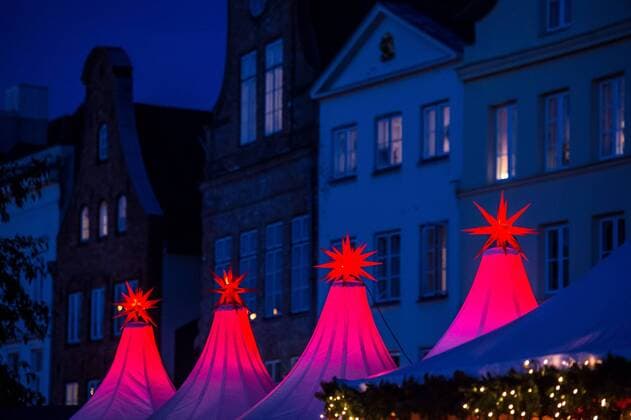 Luebeck Christmas market a Christmas star lit at 24 11 2016 on the Christmas Wonderland to the Obertrave in before the Old Town backdrop in Luebeck Luebeck Schleswig Holstein Germany