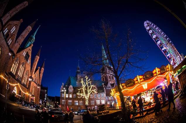 Luebeck Christmas market a Ferris wheel revolves to at 27 11 2016 on the maritime Christmas market on the Koberg in Luebeck before the St Jakobi Church and the Saints Spirit Hospital in Luebeck Date with a 16 MM Fisheye Lens Luebeck Schleswig Holstein Germany