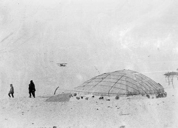 SS Chelyuskin , a Soviet steamship sent out on an expedition to navigate through polar ice along the Northern Maritime Route from Murmansk to Vladivostok , has became ice-bound in Arctic waters during navigation . It was caught in the ice fields in September. After that it drifted in the ice pack before sinking on February 13 , 1934, crushed by the icepacks near Kolyuchin Island in the Chukchi Sea . The crew managed to escape onto the ice and built a makeshift airstrip using only a few spades , ice shovels and two crowbars , which helped in the rescue of the crew . Fifty three men walked over the ice with stores on husky sleds . Photo shows ; Members of the expedition looking at a rescue plane as it makes a pass over the camp . 24 March 1934, Russia Federation Copyright: Topfoto  UnitedArchivesEU038092
