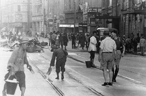 A rehabilitation squad cleaning up in the Nanking Road, Shanghai, after an air raid. A pilot debriefing in the background. After each raid, the streets are filled with debris and human victims of the bonds. 10 September 1937, China Copyright: Topfoto  UnitedArchivesEU051131