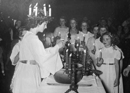 Swedes celebrate St Lucia s day. Crown of lighting candles. The Swedish festival of St Lucia s Day was observed in traditional fashion by the Swedish colony in Berlin. On this day, a feminine member of each Swedish family is chosen to be the Lucia . Dressed in white and wearing a crown of lighting candles, she distributes coffee and Lucia Cakes. The festival is actually a prelude to Christmas and symbolised the returning sunlight. Photo shows, the Lucia , wearing her Crown of lighting candles, distributing the Lucia Beveridge two Swedish girls holding candles in Berlin. 6 December 1937, Germany Copyright: Topfoto  UnitedArchivesEU056030