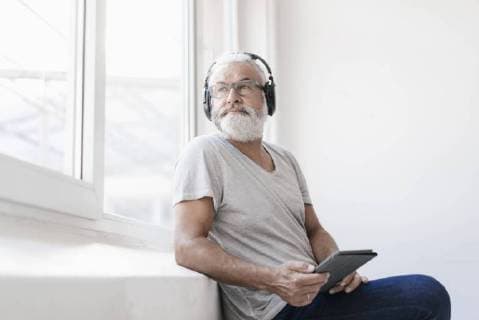 Mature man with tablet and headphones looking out of window model released Symbolfoto property released  JOSF01731