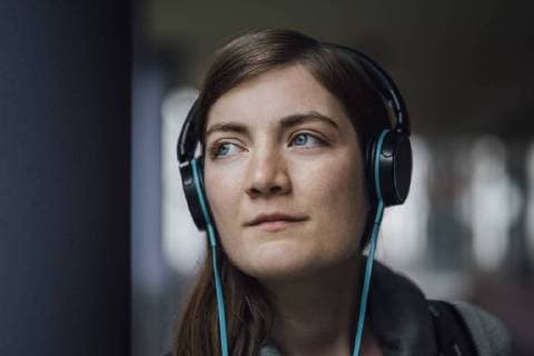 Portrait of daydreaming young woman listening music with headphones model released Symbolfoto  JSCF00005