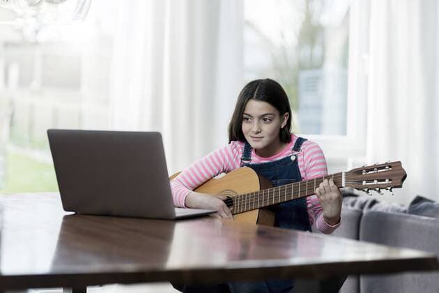 Girl playing guitar in front of laptop model released Symbolfoto property released  SBOF00641