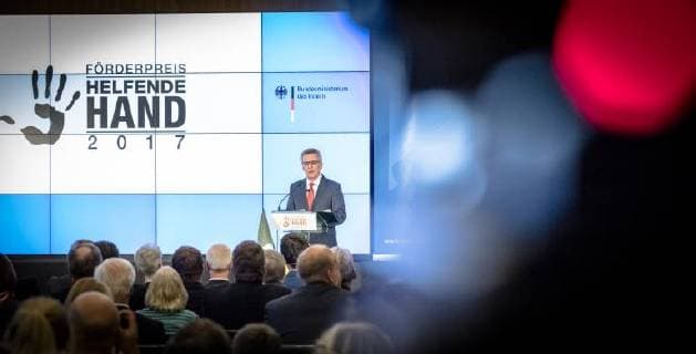 Helping Hand 2017 Federal Minister of the Interior Thomas de Maiziere Federal Minister of the Interior Dr Thomas de Maiziere awards the Foerderpreis Helfende Hand 2017 in Berlin This years Foerderpreis is awarded to ideas and concepts that arouse peoples interest in volunteering in population protection