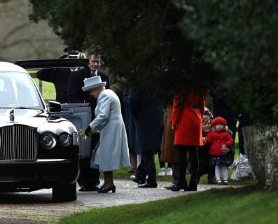 HM Queen Elizabeth II, carries a bunch of daffodils that were given to her from the little girl in red (right) after she left the St. Mary Magdalene Church Sunday morning service, on Christmas Eve, in Sandringham, Norfolk, on December 24, 2017. 