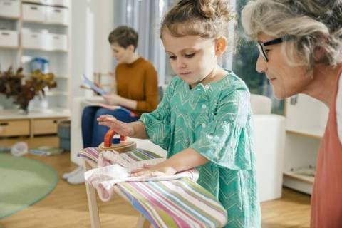 IMAGO Creative: Haushaltsgeräte, Bügeleisen Teacher watching girl ironing in kindergarten model released Symbolfoto property released  MFF04075