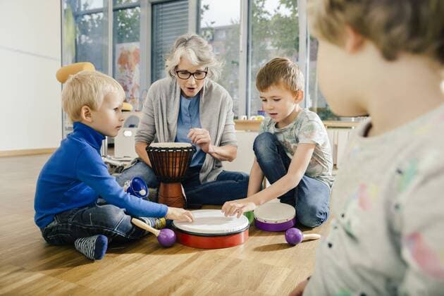 Children using percussion instruments with instructor in music room of a kindergarten model released Symbolfoto property released  MFF04081