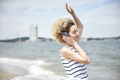Portrait of young blond woman with headphones on the beach model released Symbolfoto  TSFF00173