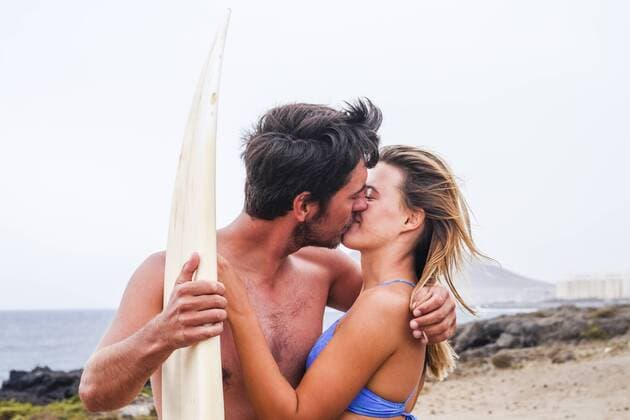 Young couple with surfboard kissing on the beach model released Symbolfoto  SIPF01810