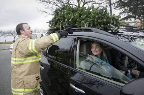 (180107) -- RICHMOND, Jan. 7, 2018 -- A firefighter removes a tree from a car during the annual Christmas tree chipping event in Richmond, Canada, Jan. 6, 2018. Collected trees will be chipped and recycled for turning them into resources. ) (zcc) CANADA-RICHMOND-CHRISTMAS TREE-CHIPPING LiangxSen 