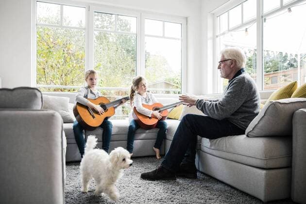 Two girls on sofa playing guitar with grandfather and dog model released Symbolfoto property released  MOEF00522