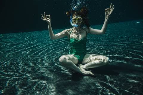 Woman with diving goggles and snorkel sitting in yoga pose underwater in a swimming pool model released Symbolfoto  MFF04253