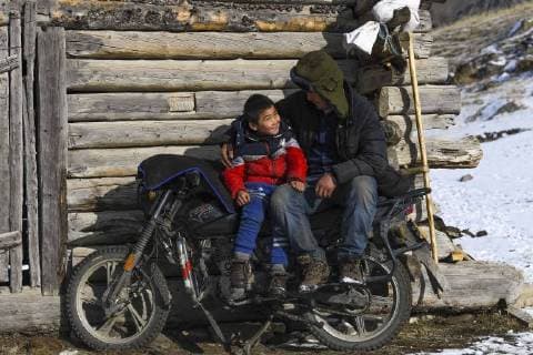 (180203) -- ILI, Feb. 3, 2018 -- A seven-year-old boy enjoys the sunshine with his father in Akyaz Valley, Zhaosu County, northwest China s Xinjiang Uygur Autonomous Region, Jan. 18, 2018. About 130 kilometers from the nearest town, Akyaz Valley is an important winter grazing place for herders in Zhaosu County, Xinjiang. Despite an altitude of 2,000 meters, the Akyaz Valley has a warmer climate than surrounding areas and abundant grass and water. It is sometimes referred to as the valley of life. For centuries, herding has been an ancestral tradition for nomadic Kazakhs in Zhaosu. Migration begins in October, and more than 10,000 people drive 400,000 cattle and sheep to their winter homes, not leaving until May the next year. ) (wyo)(zt) CHINA-XINJIANG-AKYAZ VALLEY-WINTER GRAZING (CN) HuxHuhu 
