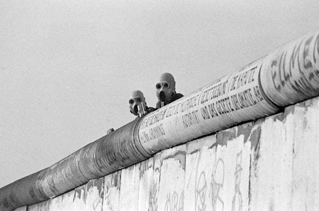 Berlin Wall June 1988 GDR border guards observe violent clashes between the West Berlin police and the autonomous squatters of the Lenné triangle at Potsdamer Platz on the wall with gas masks attached