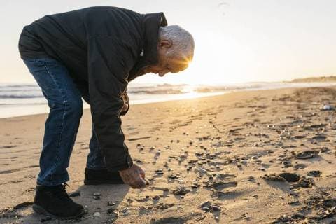 Senior man strolling at the beach, collecting shells model released Symbolfoto  JRFF01522