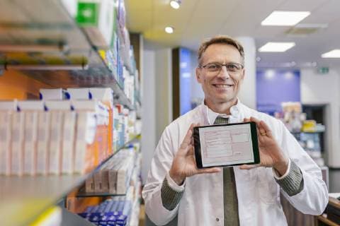 Portrait of smiling pharmacist in pharmacy holding tablet with digital prescription model released Symbolfoto property released  MFF04351