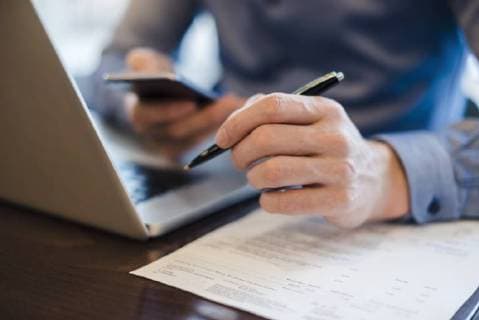 Man at desk using cell phone and holding ball pen in his hand, close-up model released Symbolfoto  DIGF03220