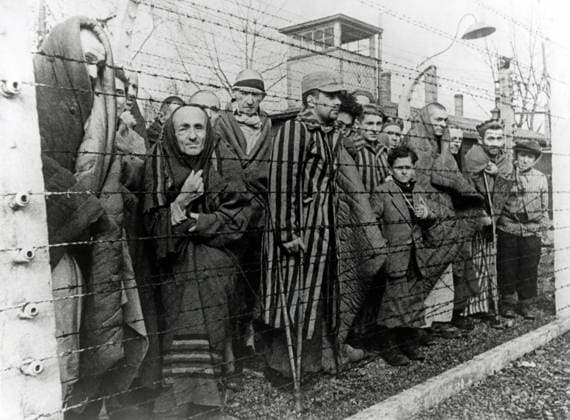 Survivors of Auschwitz behind barbed wire fence Photo taken by a Soviet photographer while making a film about the liberation of the camp Auschwitz Poland Date of February 1945