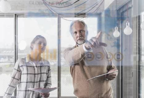 IMAGO Creative: Corporate: Klimaschutz, Digitalisierung und Urbanisierung Casual mature businessman and young woman discussing data at glass pane in office model released Symbolfoto property released  UUF12774
