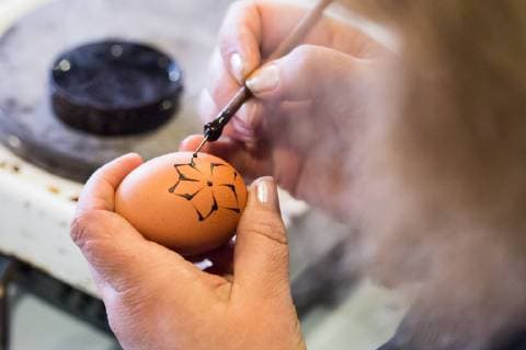 Easter eggs adorned in traditional batik technique, called penganje , specific for the Dubrovnik region Konavle - Dubrovnik, Croatia 27.03.2018., Dubrovnik, Croatia - Coloring of easter eggs, so called penganje , specific for the Dubrovnik region Konavle. Easter eggs are adorned in traditional batik technique that requires wax and bowl in which wax is wiped, color and eggs. The design begins with the needle stuck in a wooden stand or a wooden pen and drowns in rapid movements into a wax that needs to be constantly in the liquid state, than egg is sliced into wax, then the wax is applied to the egg in different decorations. Waxed eggs are placed in water with a color, then warmed slightly until the wax is dissolved, sliced from the egg and left only decorated part.  GrgoxJelavic PIXSELL