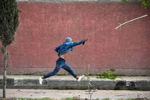 April 5, 2018 - Srinagar, J&K, India - A Kashmiri student protester throws a wooden stick towards government forces during clashes in Srinagar, Indian administered Kashmir. Fierce clashes broke out between government forces and students in Srinagar on Thursday as the valley continued to remain tense over the killing of 17 people including 13 militants and 4 civilians in separate encounters in south Kashmir. Police used tear smoke shells to chase away the protesters. The violence rocked Kashmir valley on the day when authorities lifted restrictions after four days of the shutdown. Srinagar India - ZUMAs197 20180405_zaa_s197_046 Copyright: xSaqibxMajeedx