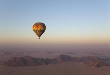Hot air balloon over a dry plain and lonely ridge at daybreak. Namib desert. Aerial view NamibRand Nature Reserve Namibia Africa Copyright: imageBROKER/ThomasxDressler ibltdr04661226.jpg