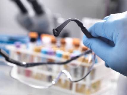 Medical technician holding protective glasses with human samples on the laboratory bench model released Symbolfoto property released  ABRF00140