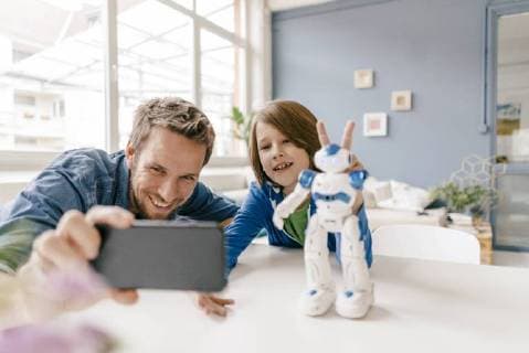 Happy father and son taking a selfie with robot on table at home model released Symbolfoto property released  KNSF03584
