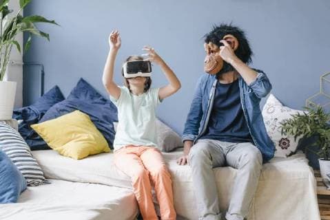 Father wearing monkey mask looking at son wearing VR glasses at home model released Symbolfoto property released  KNSF03646