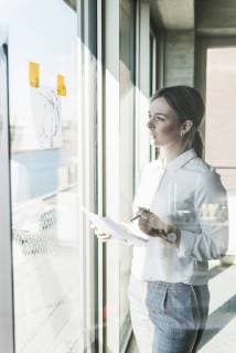 Young businesswoman looking at paper at the window model released Symbolfoto property released  UUF13113