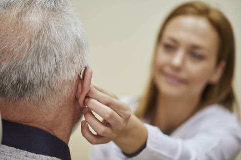 Female doctor applying hearing aid to senior man s ear model released Symbolfoto property released  ZEDF01253