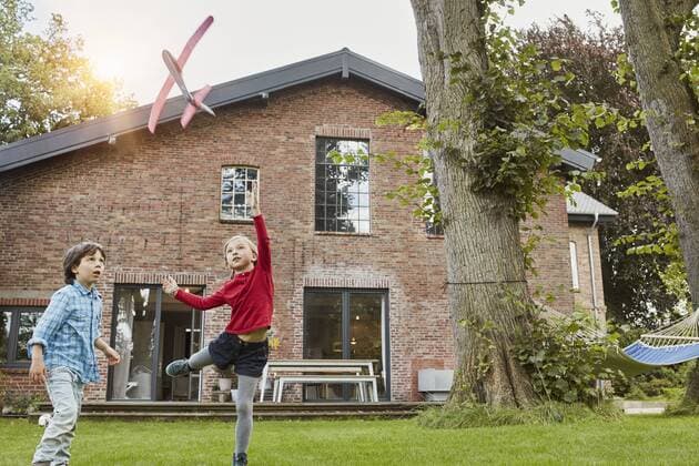 Two children playing with toy airplane in garden of their home model released Symbolfoto property released  RORF01206