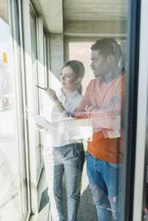 Casual businesswoman and businessman discussing paper at the window model released Symbolfoto property released  UUF13112