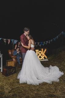 Romantic wedding couple embracing on a night field party with their friends in the background model released Symbolfoto property released  DAPF00939